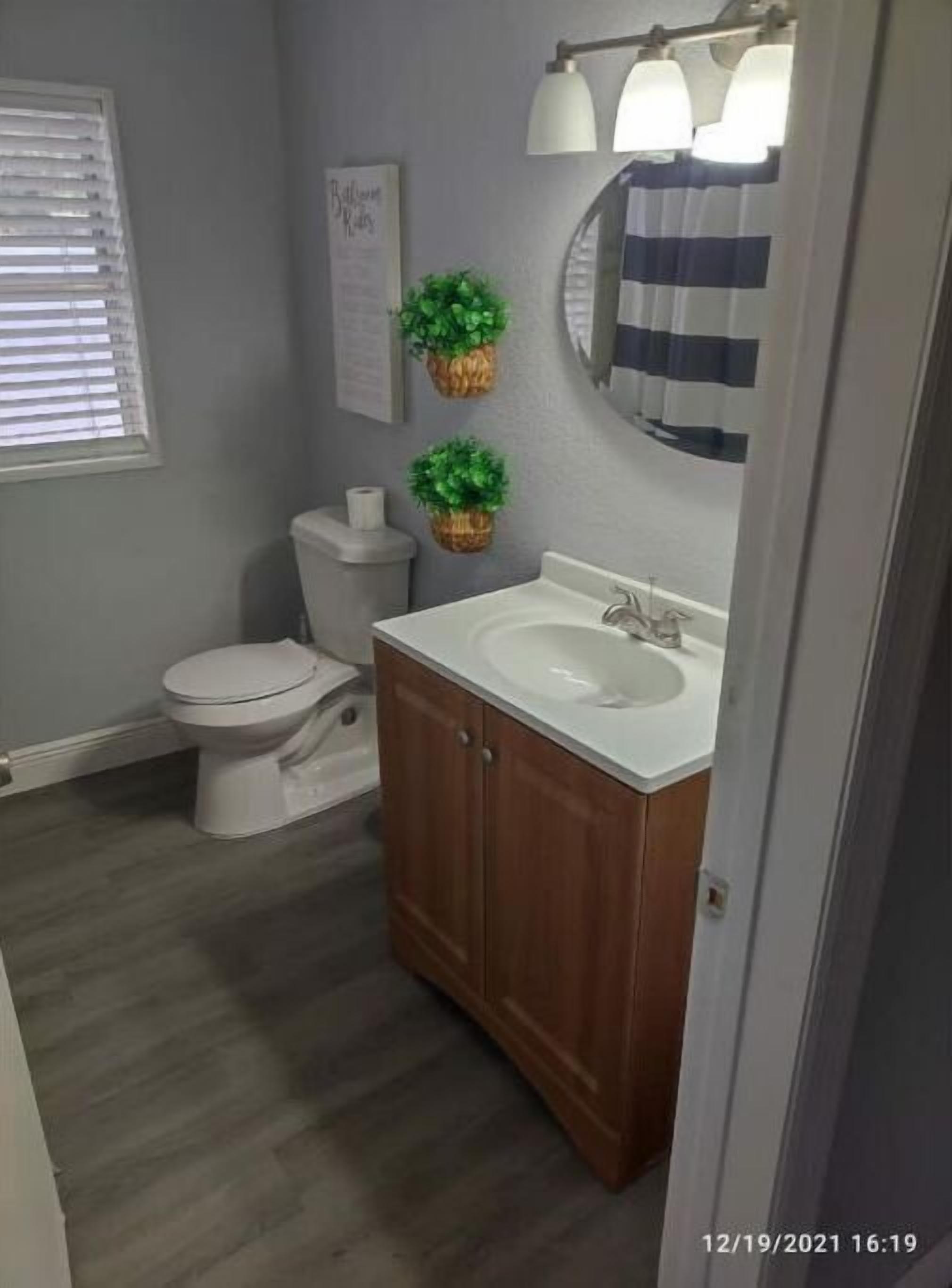 A bathroom with a toilet, sink, and mirror.