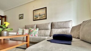 Una sala de estar con un sofá color beige, una mesa de centro de madera y un cuadro en la pared.
