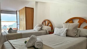 A hotel room with two beds, each with a wooden headboard, a large window, and a view of the beach. - Casa Rural Con Jardín Y Barbacoa - A Babor 20805 (Cantabria)