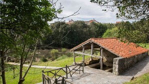 A rustic stone building with a tiled roof, surrounded by greenery and a stone pathway. - Casa Rural Con Jardín Y Barbacoa - A Babor 20805 (Cantabria)