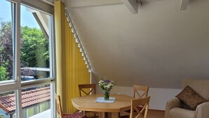 Un comedor con una mesa redonda, cuatro sillas de madera y un jarrón de flores.