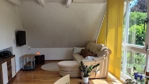 Una sala de estar moderna con un sofá, un reposapiés y una planta en maceta.