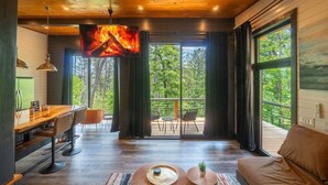 A modern interior with a wooden ceiling, a dining area with bar stools, a sofa, and a large window offering a view of the outdoors.