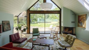 A spacious living room with a high ceiling, large windows, a fireplace, and a variety of seating options. - La Maison de L'amiral (Moëlan-sur-Mer)