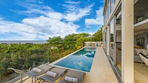 A modern pool area with lounge chairs and a view of the ocean. - Stunning contemporary villa with incredible views over the Barbados West Coast (Lower Carlton)