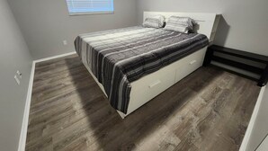 Un dormitorio con cama, ventana y suelo de madera.