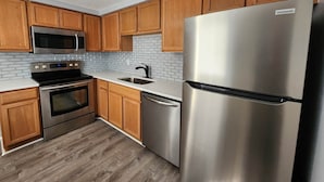 Una cocina con armarios de madera, un refrigerador de acero inoxidable, un microondas, un horno y un lavavajillas.