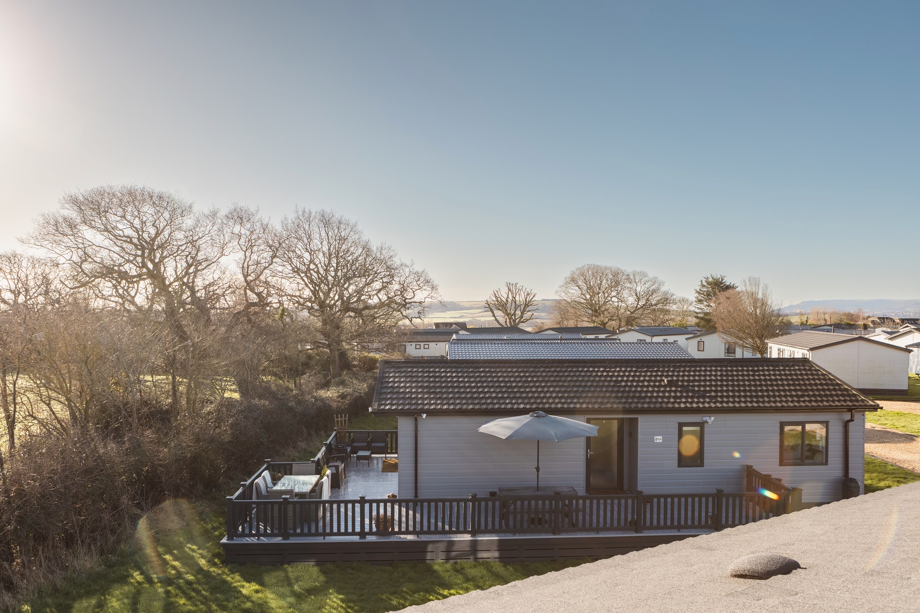 A single-story house with a patio, a small deck, and a covered outdoor seating area.