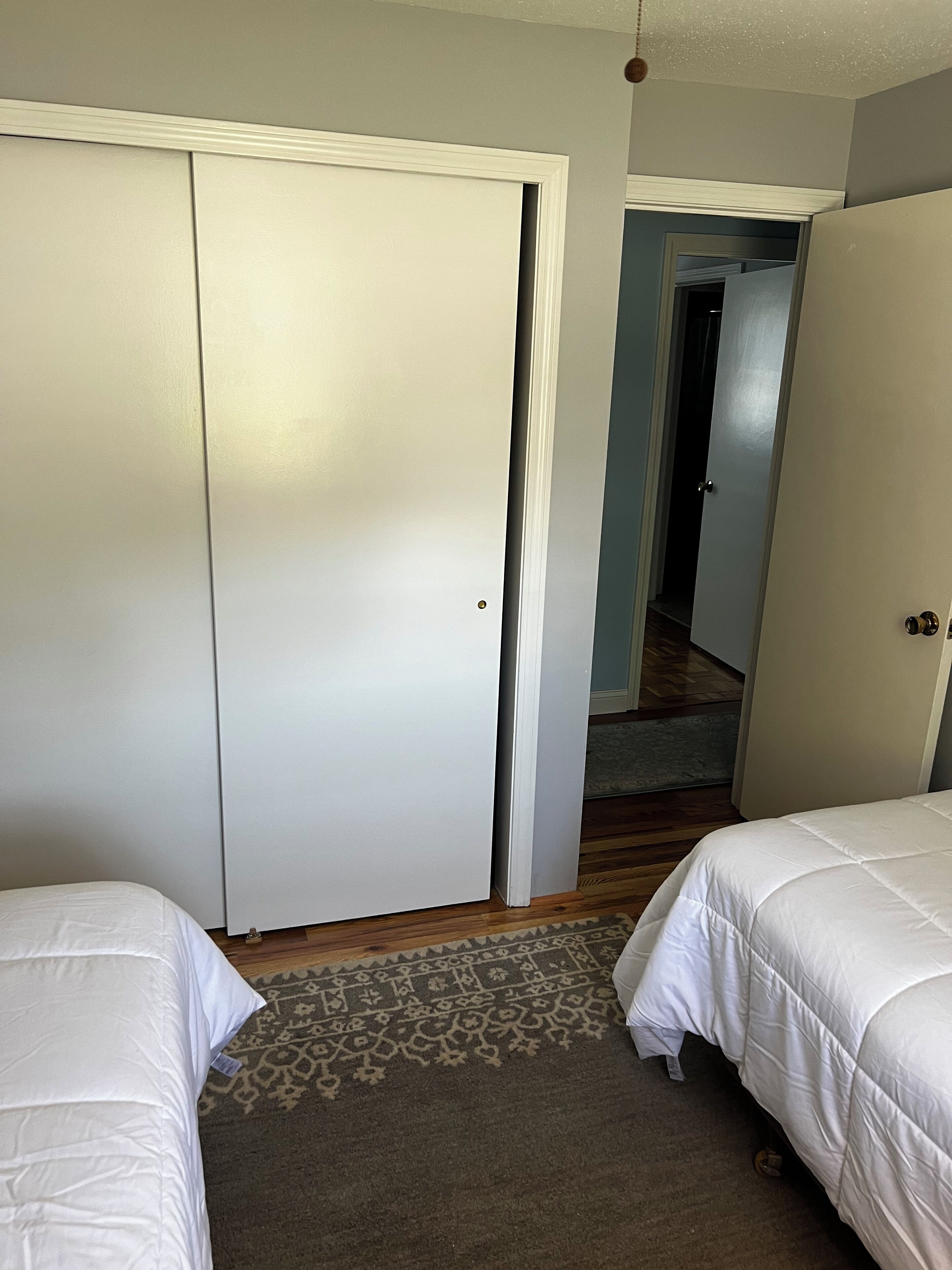 A bedroom with two beds, a wardrobe, and a carpeted floor.