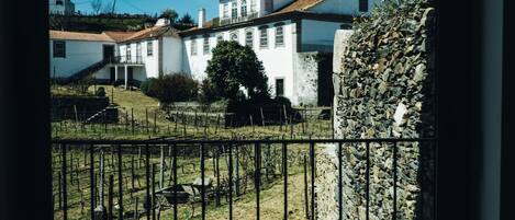 A view of a white building with a red roof, a stone wall, and a metal fence in the foreground.
