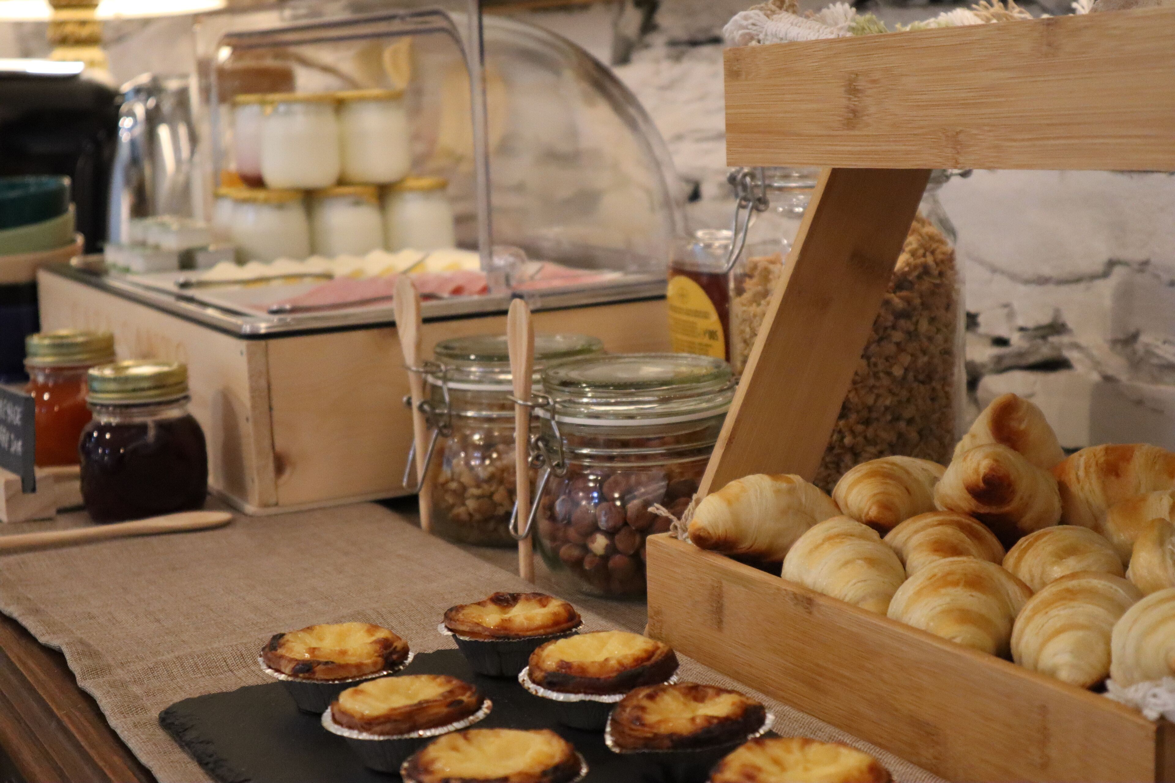 A buffet with pastries, including croissants and tarts, and various condiments in jars.