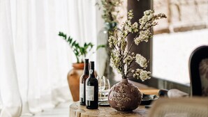 A cozy seating area with a round wooden table, a vase with flowers, and two wine bottles. - Casa do Santo - Wine & Tourism (Sabrosa)