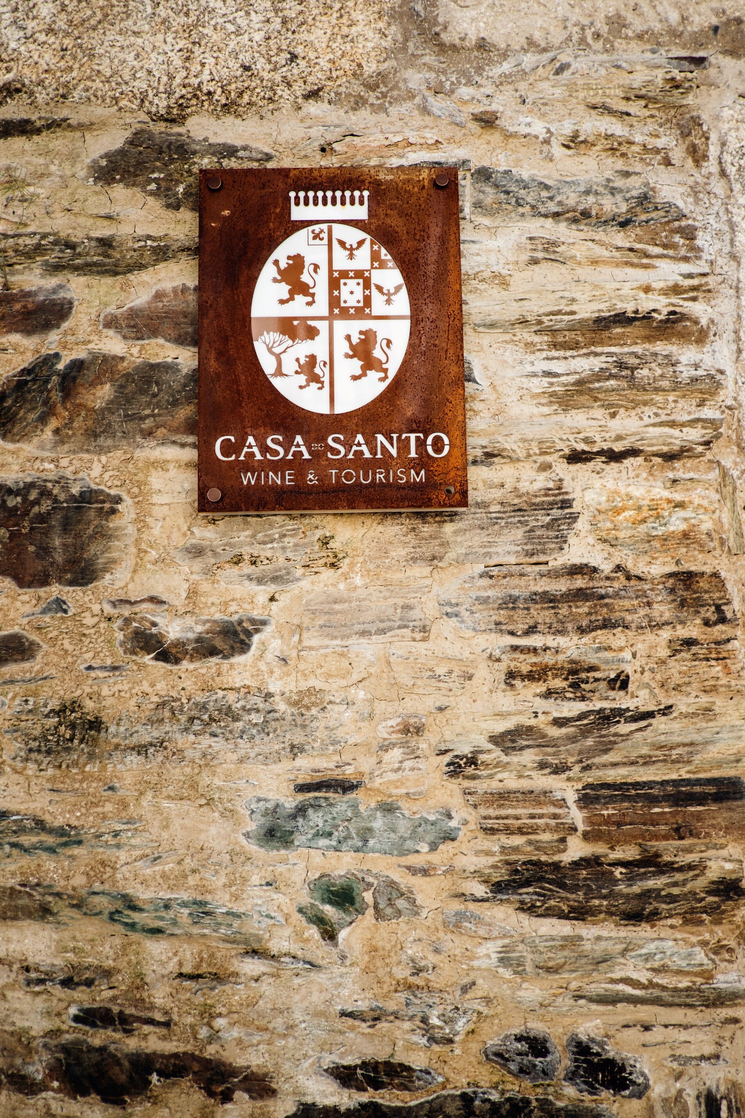 A sign for Casa Santo Wine & Tourism on a stone wall.