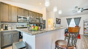 A modern kitchen with granite countertops, stainless steel appliances, and a central island with bar stools.