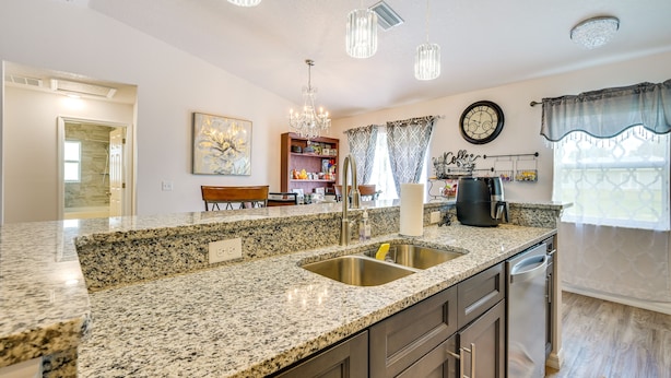 A kitchen with granite countertops, stainless steel appliances, and pendant lighting.