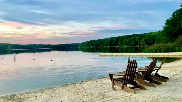 Uitzicht op een meer met houten stoelen in het zand.