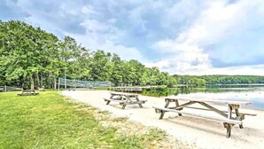 Een park aan het meer met picknicktafels, een volleybalnet en een rustig meer.