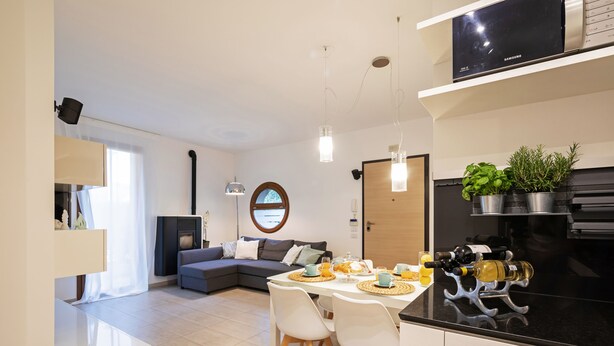 A modern kitchen with a dining area, a built-in TV, and a fireplace. - Martilla - Two Bedroom Apartment, Sleeps 5 (Gabicce Mare)
