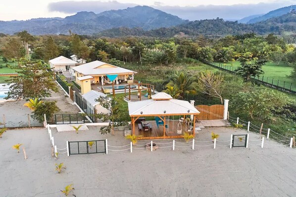 A resort with multiple buildings, a swimming pool, and a fenced area with a gazebo.