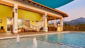 A pool area with a covered seating area and a view of mountains in the background. - Spectacular oceanfront home (Omoa)