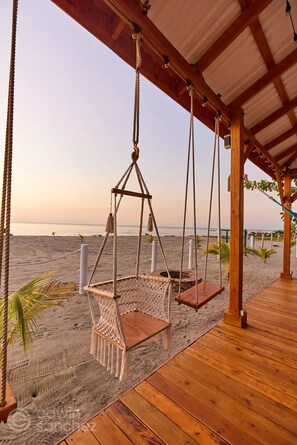 A wooden deck with a swing chair overlooking a beach. - Spectacular oceanfront home (Omoa)