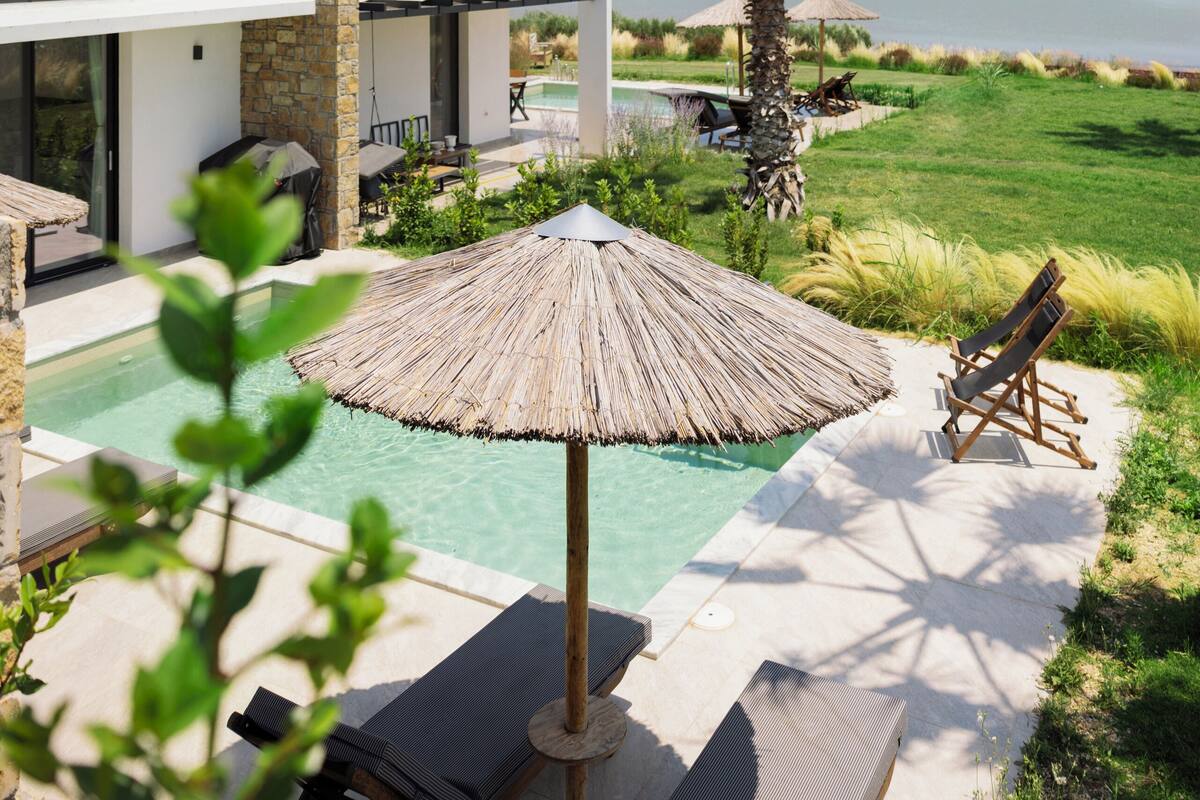 Una casa moderna amb piscina, mobiliari exterior i vistes al mar.