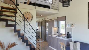 A modern interior with a staircase, living room, kitchen, and dining area.