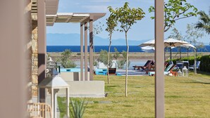 Un área junto a la piscina con sillones de descanso, sombrillas y vista al mar.