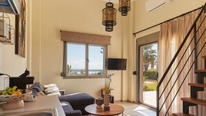 Una sala de estar moderna con un sofá, una mesa de centro y vistas al exterior a través de un amplio ventanal.