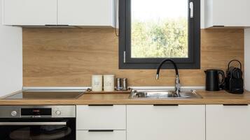 Cocina moderna con armarios blancos, un grifo negro, un horno Bosch y una ventana con vistas a zonas verdes.
