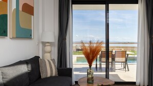 Una sala de estar moderna con un sofá, una mesita de centro con adornos y vistas a una piscina y un área de estar exterior.
