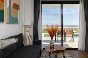 Una sala de estar moderna con un sofá, una mesita de centro con adornos y vistas a una piscina y un área de estar exterior.