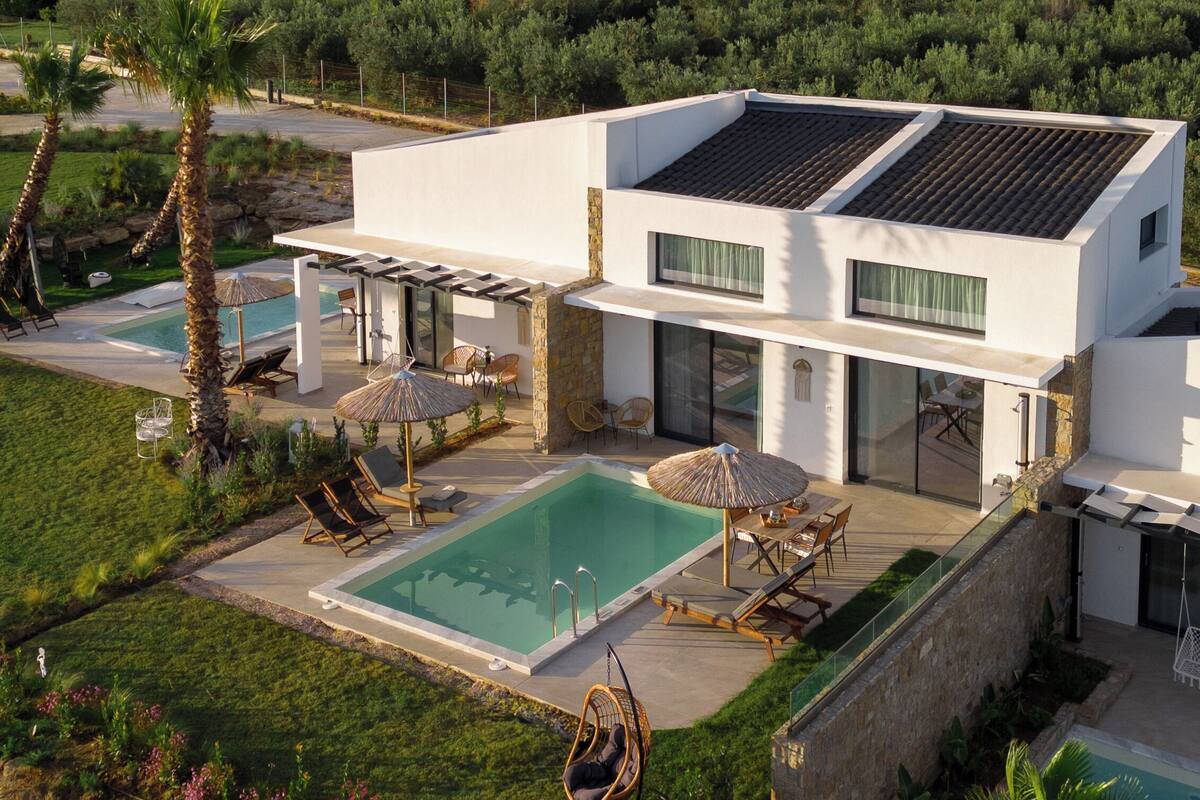 Una casa moderna de dos pisos amb piscina, mobiliari exterior i vistes al camp.