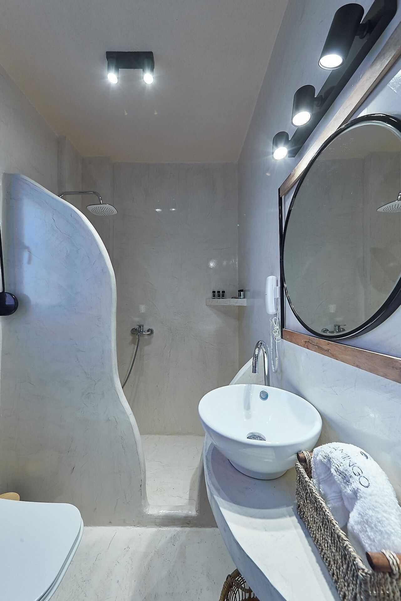 A modern bathroom with a curved shower, a white sink, and a large mirror.