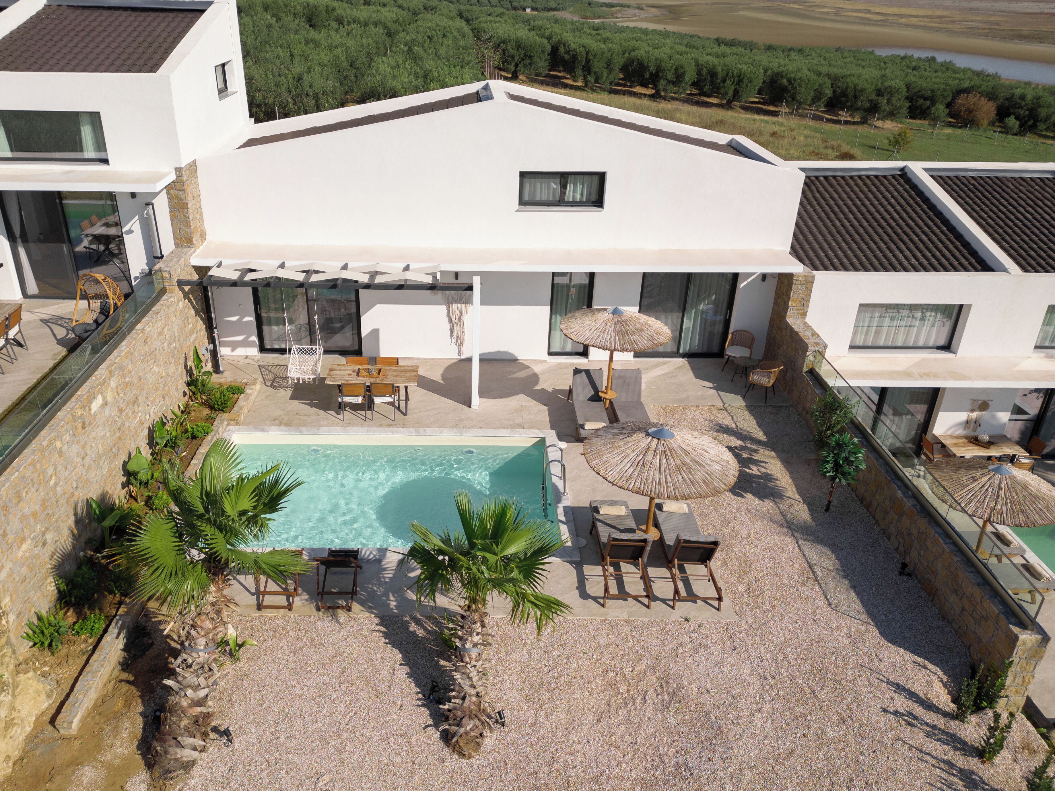 A modern house with a swimming pool, outdoor seating, and a view of the surrounding landscape.
