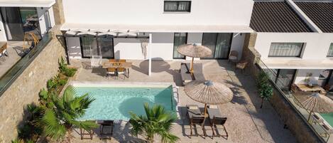 A modern house with a swimming pool, outdoor seating, and a view of the surrounding landscape.