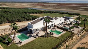 Una villa moderna con piscina, zona de estar exterior y vistas del paisaje circundante.