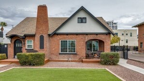 A two-story brick house with a front porch, a chimney, and a well-maintained lawn.