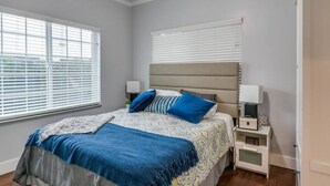 A bedroom with a bed, nightstands, and a window with blinds.