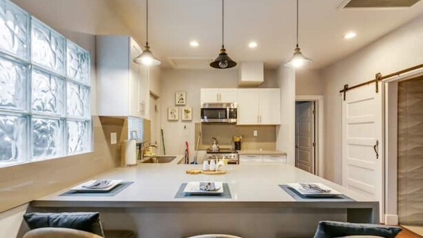 A modern kitchen with white cabinets, a central island, and pendant lighting.