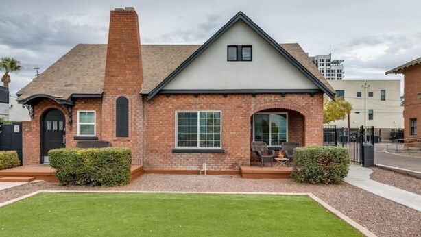 Een gelijkvloers huis met een bakstenen gevel, een zadeldak en een voortuin met een bankje.