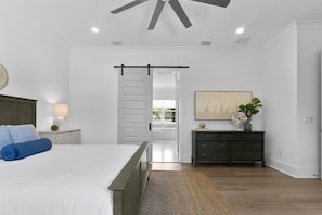 A modern bedroom with a bed, a nightstand, a dresser, and a ceiling fan. - Lavish & Spacious Home in Walkable Hyde Park (Tampa)