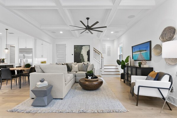 A modern living room with a sectional sofa, a coffee table, and a dining area with a wooden table and chairs. - Lavish & Spacious Home in Walkable Hyde Park (Tampa)
