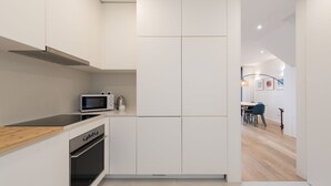 Eine moderne Küche mit weißen Schränken, einer Mikrowelle und einem Backofen.