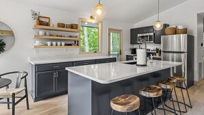 Eine moderne Küche mit einer großen Kochinsel, dunklen Schränken und einem Edelstahl-Kühlschrank.