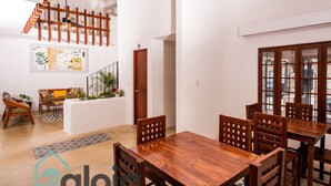 A spacious living area with a wooden dining table and chairs, a staircase, and a view of the outside. - VICA GUEST HOUSE (Cancun)