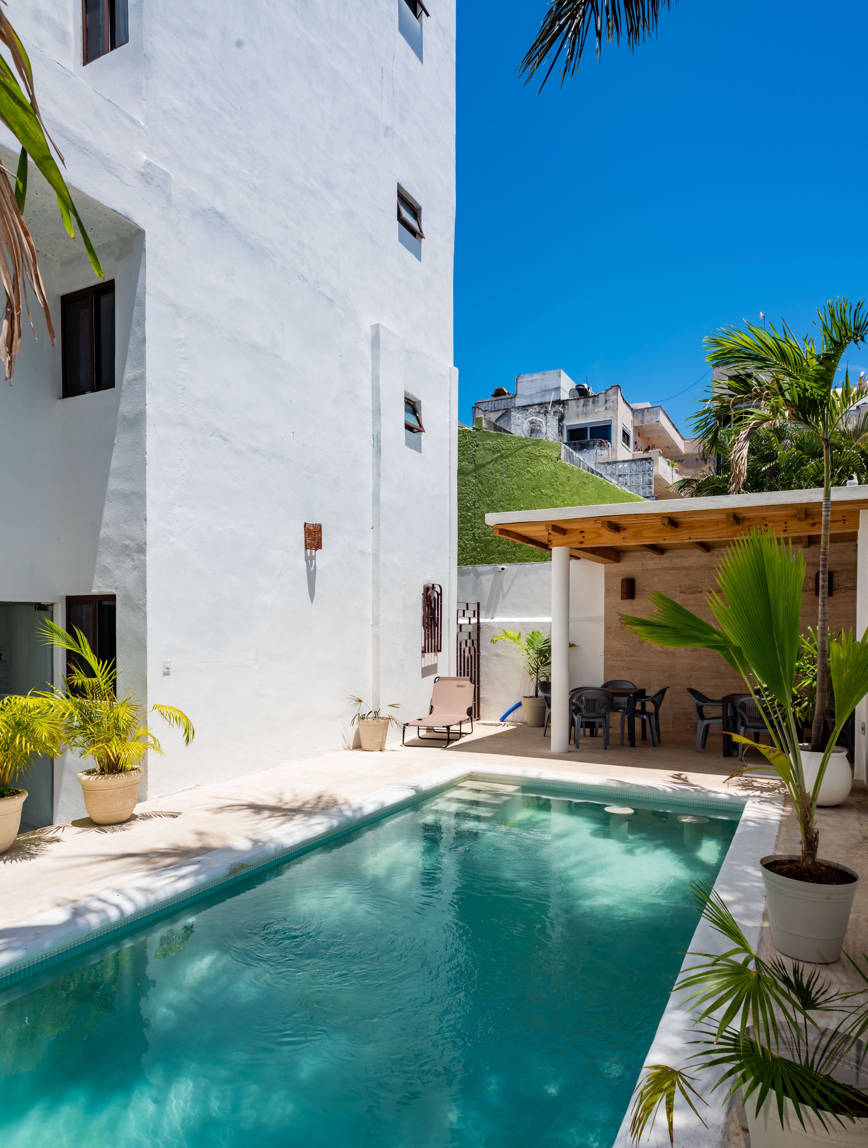 A white building with a pool, outdoor seating, and potted plants.
