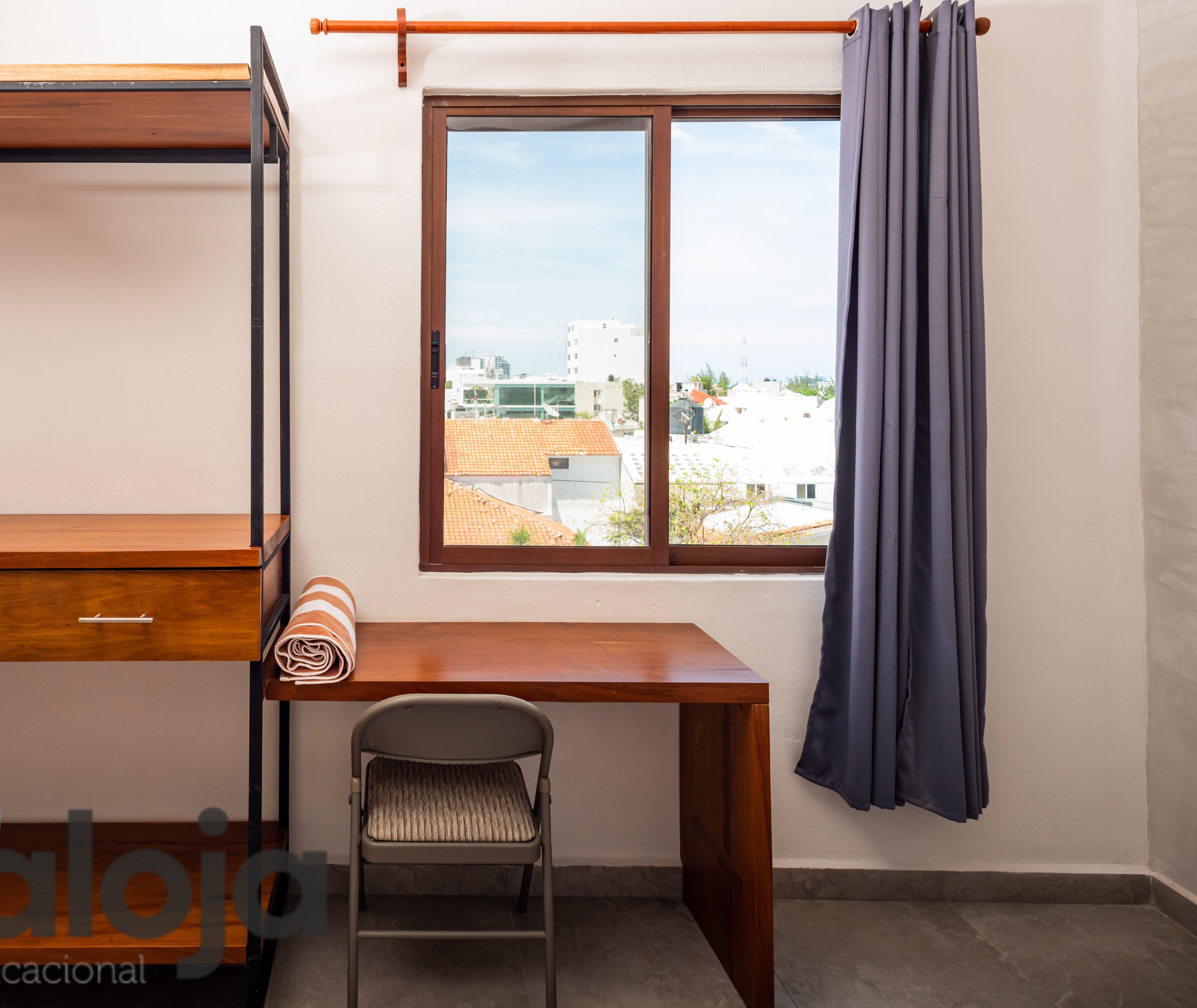 Una habitación con literas, un escritorio, una silla y una ventana con cortinas.