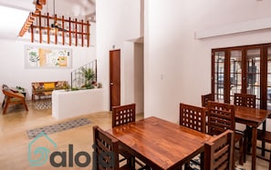 A spacious living area with a wooden dining table and chairs, a staircase, and a view of the outside. - VICA GUEST HOUSE (Cancun)