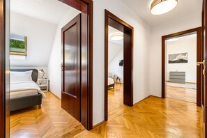 Une chambre d’hôtel avec un lit, une table de chevet et une vue sur une autre chambre par une porte ouverte.